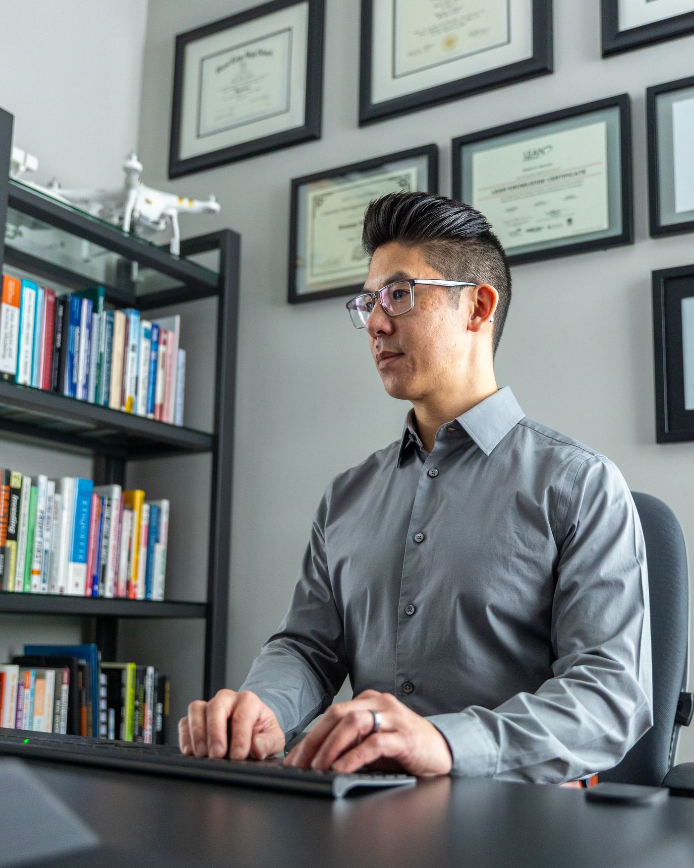 Donny C. Nguyen writing at his desk beside a shelf of business books